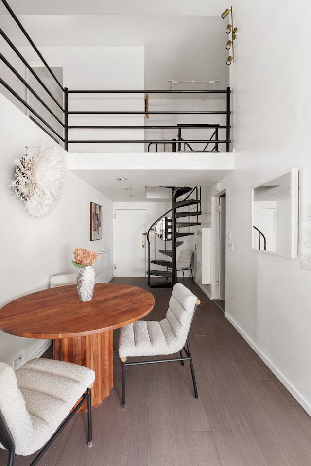 dining area with stairs, wood finished floors, baseboards, and a towering ceiling