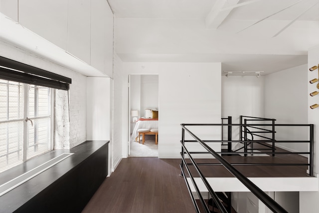 interior space featuring an upstairs landing, dark wood-style floors, and beam ceiling