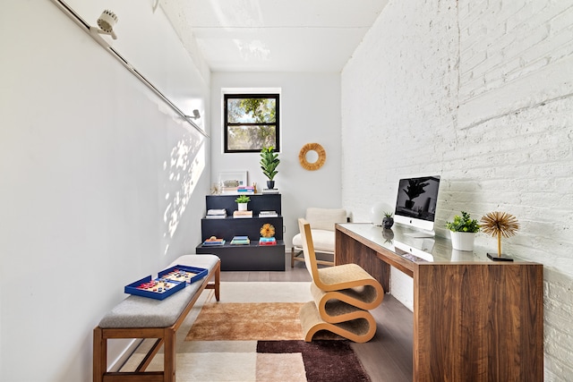 home office with wood finished floors and brick wall