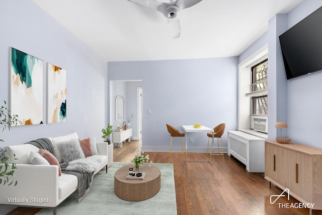 living room with cooling unit, baseboards, wood finished floors, and ceiling fan