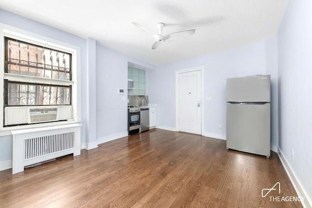 unfurnished living room with ceiling fan, radiator, wood-type flooring, and cooling unit