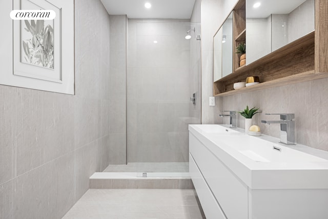 bathroom featuring double vanity, tile walls, a walk in shower, and a sink