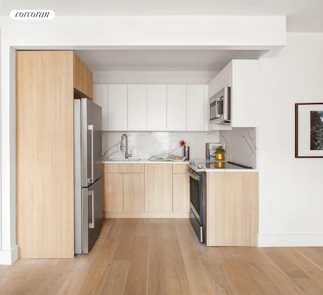 kitchen with stainless steel appliances, light countertops, white cabinetry, a sink, and modern cabinets