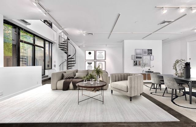 carpeted living area featuring rail lighting, visible vents, and stairs