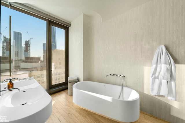 bathroom with vanity, a bath, hardwood / wood-style flooring, and a wall of windows