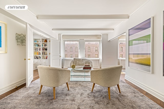 sitting room with beamed ceiling, ornamental molding, built in shelves, and wood-type flooring