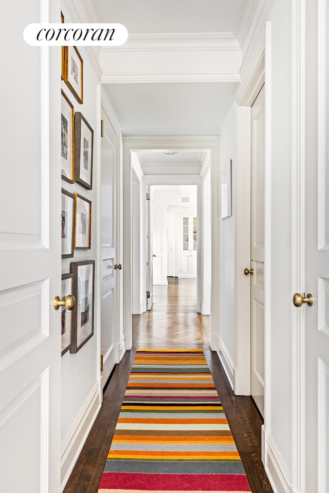 hallway with dark wood-style floors, baseboards, and ornamental molding