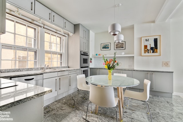 kitchen with sink, tasteful backsplash, decorative light fixtures, stainless steel dishwasher, and stone counters