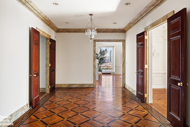 hall with a notable chandelier, crown molding, and dark parquet floors