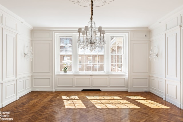 unfurnished dining area with ornamental molding, an inviting chandelier, and a decorative wall