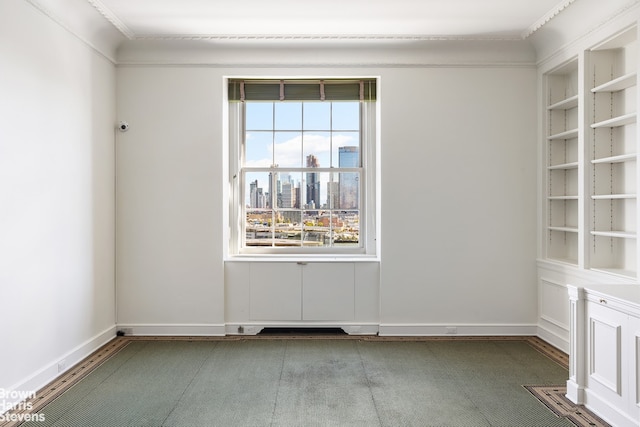 unfurnished room featuring baseboards, crown molding, built in features, and a city view