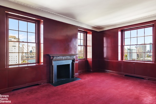 unfurnished living room with a fireplace with flush hearth, a view of city, and carpet