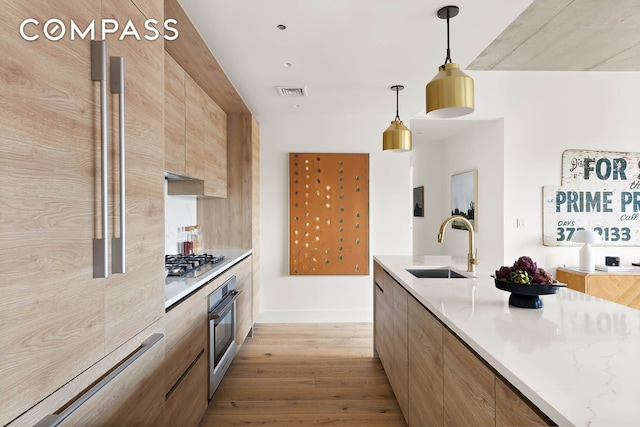 kitchen with visible vents, appliances with stainless steel finishes, light wood-style floors, a sink, and modern cabinets