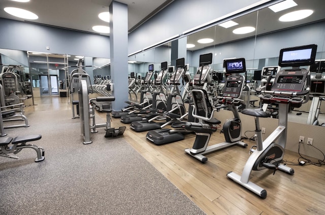 exercise room with wood-type flooring and a high ceiling