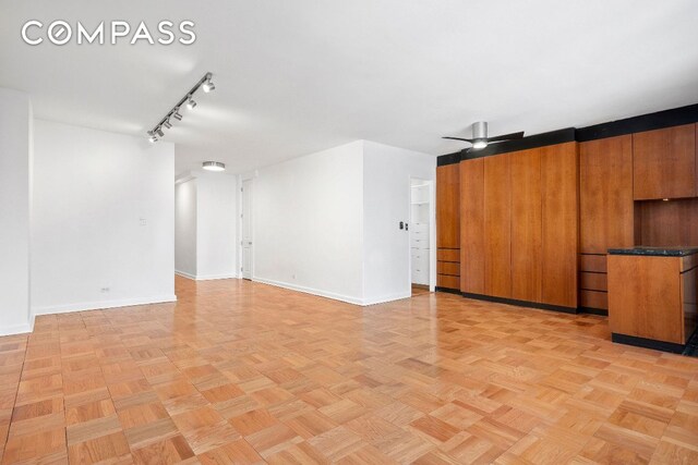 unfurnished living room featuring ceiling fan, rail lighting, and light parquet floors