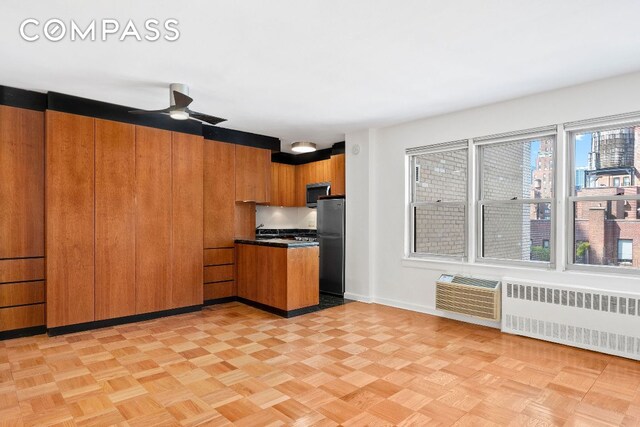 kitchen featuring a healthy amount of sunlight, radiator, black refrigerator, and ceiling fan