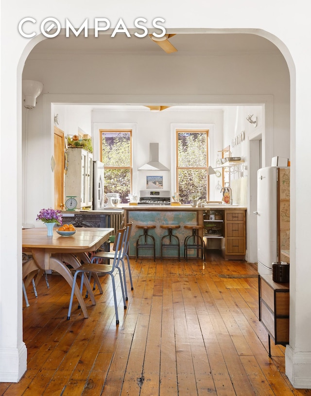 dining space with arched walkways, hardwood / wood-style floors, and crown molding