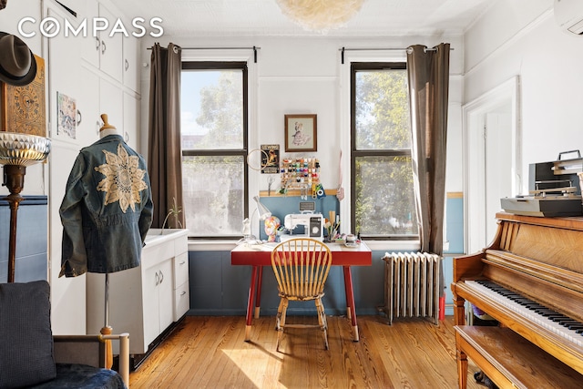 office area with a wall unit AC, radiator, and light wood-style floors