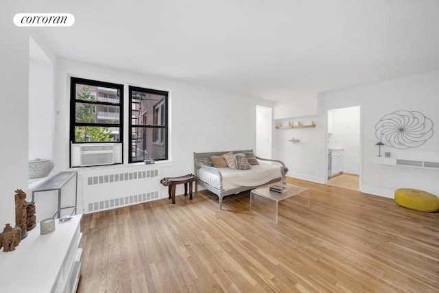 sitting room featuring cooling unit, light hardwood / wood-style floors, and radiator heating unit