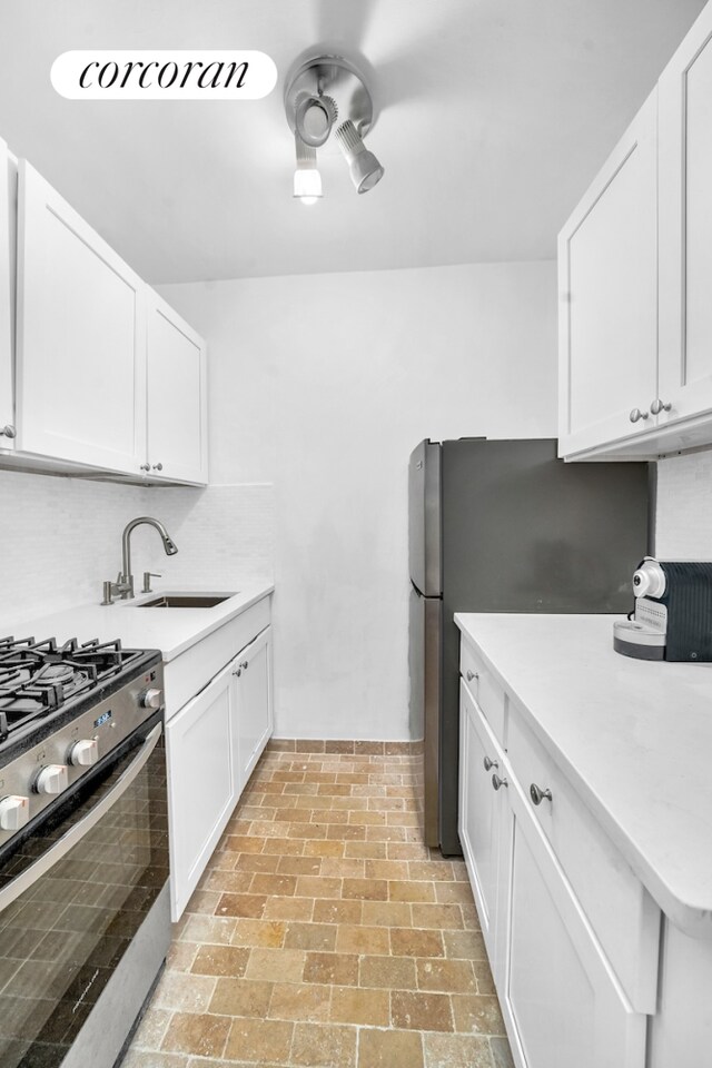 kitchen with appliances with stainless steel finishes, sink, and white cabinetry