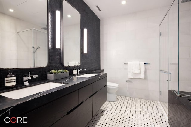 bathroom featuring a shower with door, tile walls, vanity, tasteful backsplash, and toilet