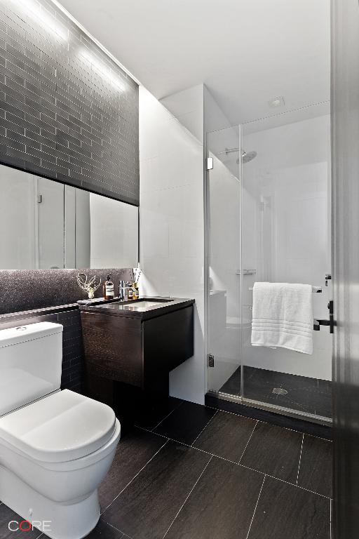 bathroom featuring vanity, toilet, a shower with shower door, and tile patterned flooring