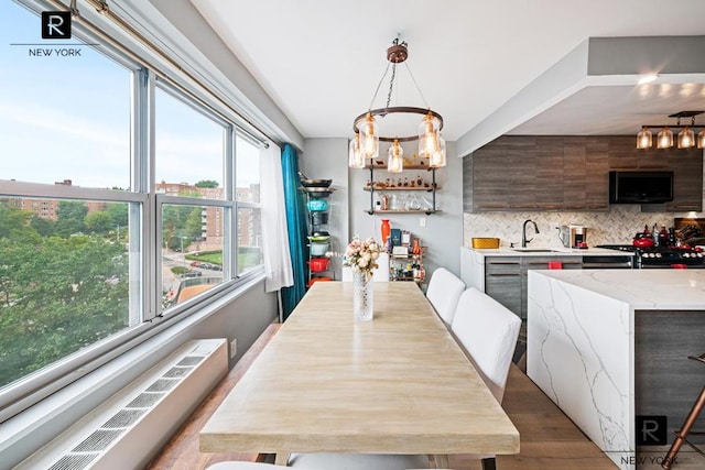 dining area with indoor wet bar, radiator, a chandelier, and hardwood / wood-style floors