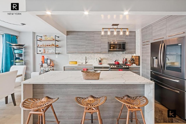 kitchen with modern cabinets, stainless steel appliances, a sink, and a center island