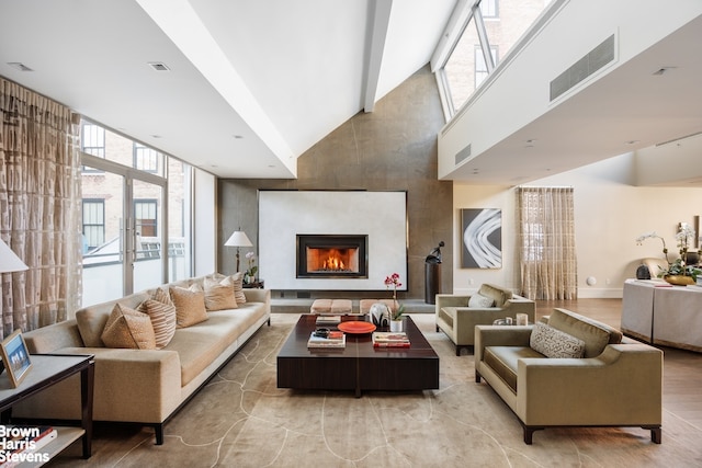 interior space with plenty of natural light, a warm lit fireplace, visible vents, and wood finished floors