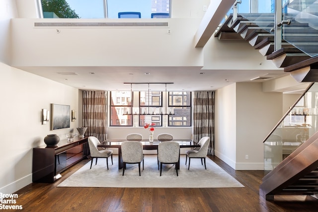 dining area with track lighting, a high ceiling, wood finished floors, and baseboards