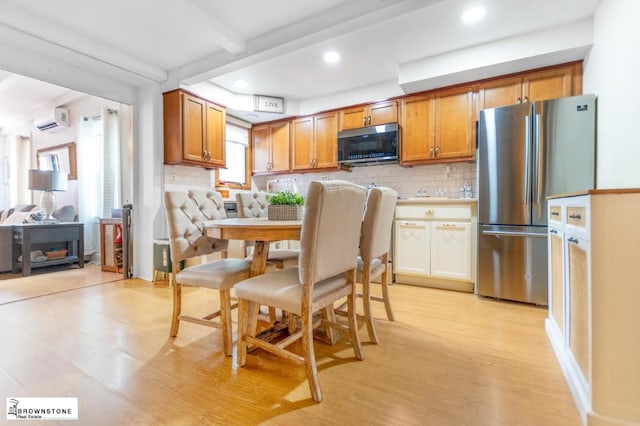 kitchen featuring light wood-type flooring, backsplash, a wall mounted AC, and appliances with stainless steel finishes