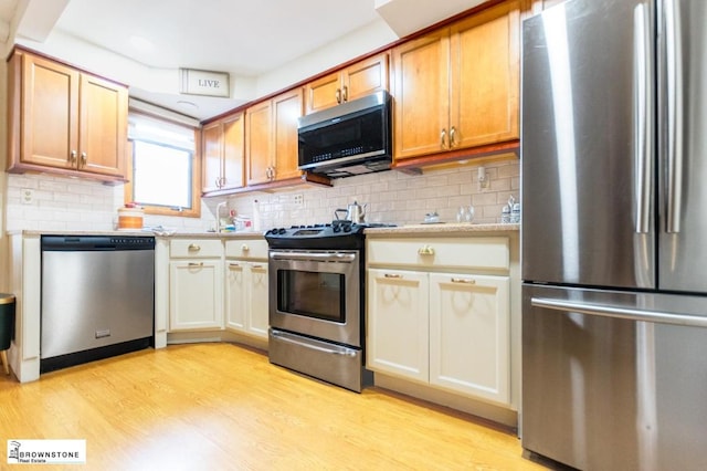 kitchen featuring backsplash, stainless steel appliances, and light wood-type flooring