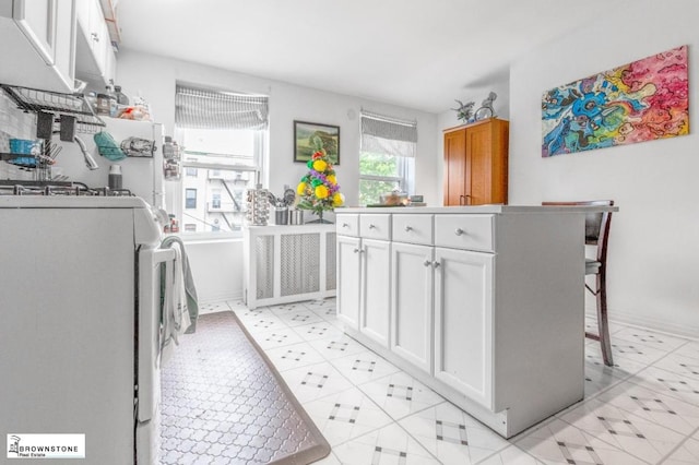 kitchen featuring a kitchen bar, white cabinets, and washer / clothes dryer