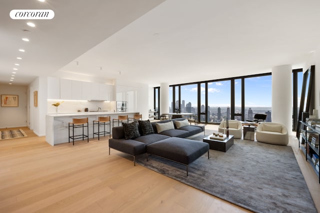 living area with light wood-type flooring, floor to ceiling windows, visible vents, and recessed lighting