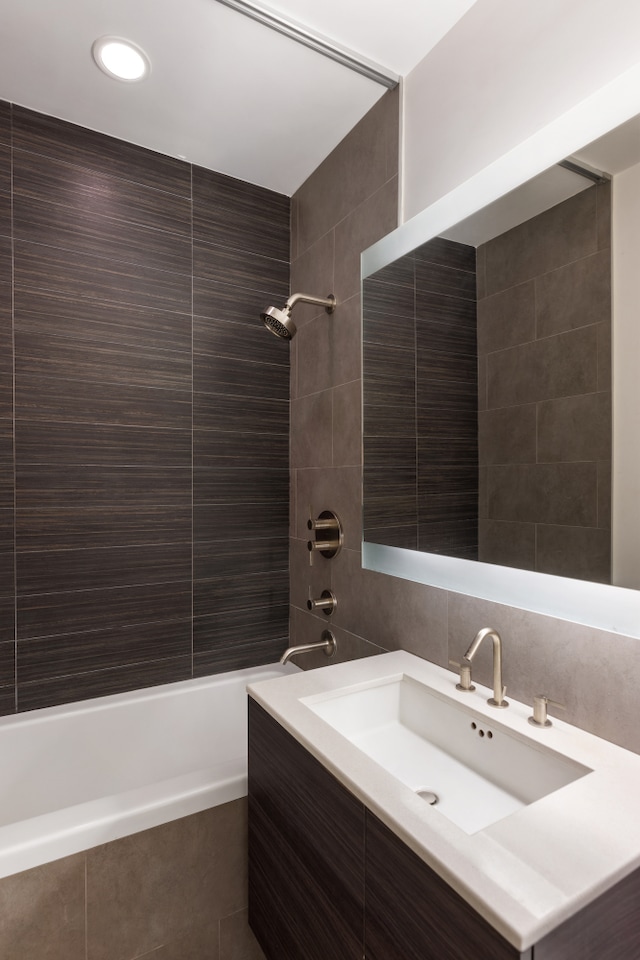 full bathroom with tiled shower / bath, decorative backsplash, tile walls, and vanity