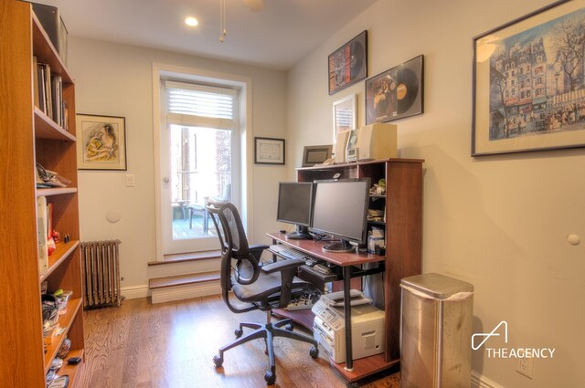 home office with radiator heating unit, baseboards, and wood finished floors