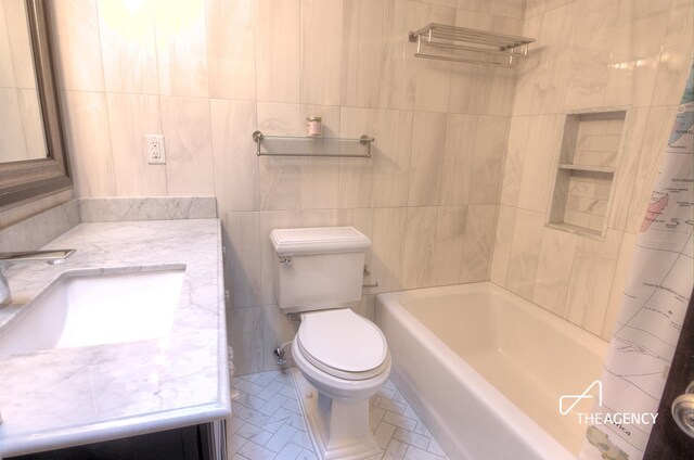 full bathroom featuring toilet, shower / bath combination with curtain, tile walls, and vanity