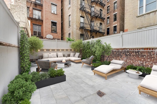 view of patio featuring fence and an outdoor living space with a fire pit