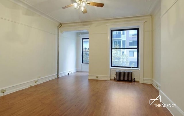 unfurnished room featuring radiator heating unit, wood finished floors, baseboards, and ornamental molding