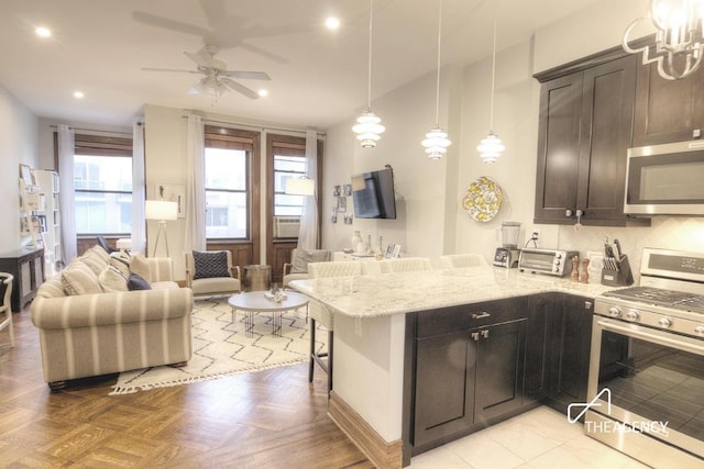 kitchen featuring appliances with stainless steel finishes, decorative light fixtures, tasteful backsplash, light parquet floors, and light stone counters