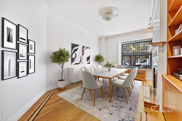 dining room with crown molding, light wood-style flooring, and baseboards