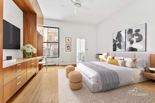 bedroom with ensuite bathroom, ceiling fan, baseboard heating, and light wood-style floors