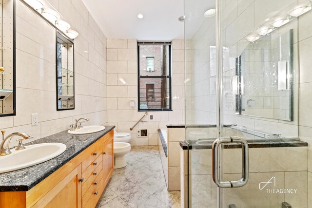 full bathroom with a bidet, tile walls, and a sink