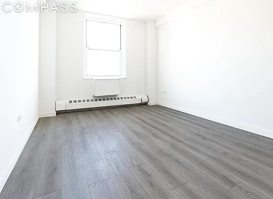 spare room featuring a baseboard heating unit and hardwood / wood-style floors