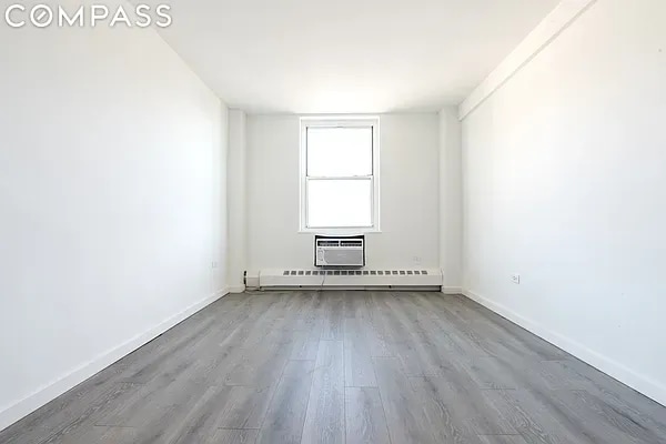 spare room featuring baseboard heating, a wall mounted AC, and light hardwood / wood-style flooring