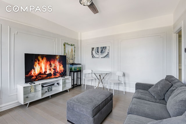 living area with a lit fireplace and light wood-style floors