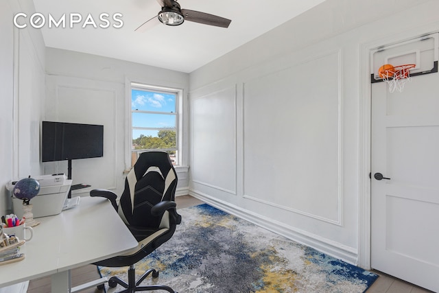 office featuring a decorative wall and a ceiling fan