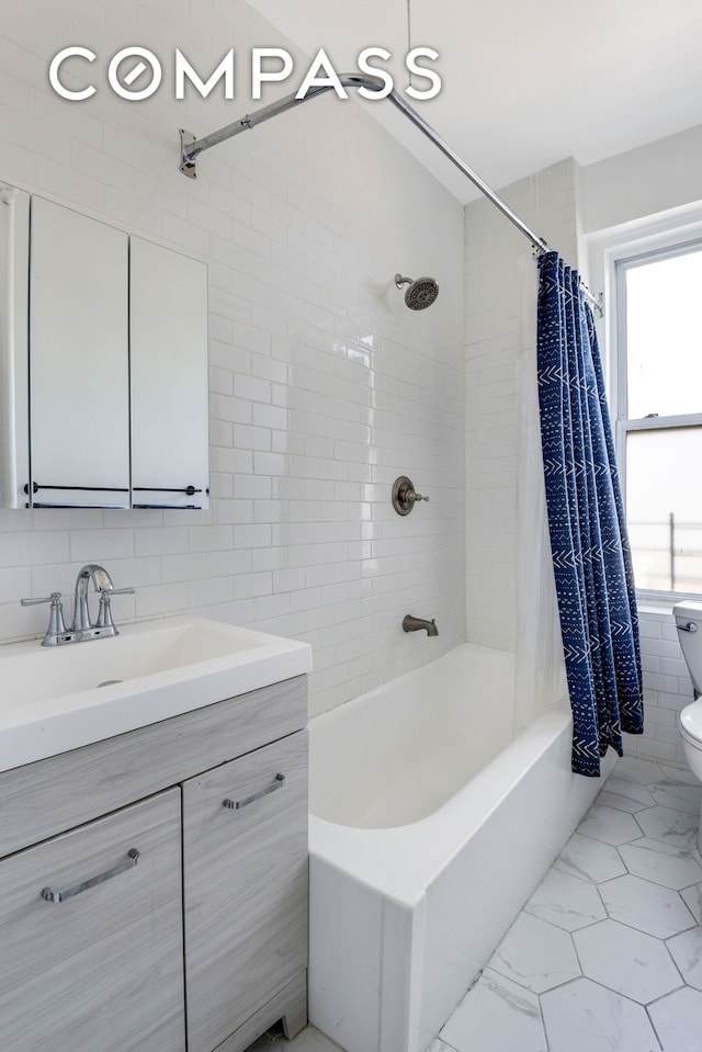 full bath featuring toilet, vanity, marble finish floor, tile walls, and shower / bathtub combination with curtain