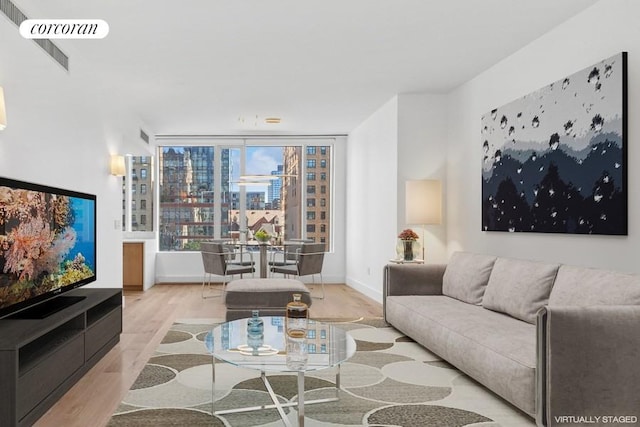 living room with light wood-style floors, baseboards, a view of city, and visible vents