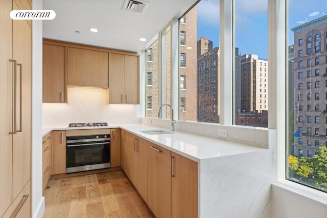 kitchen featuring visible vents, a peninsula, stainless steel appliances, a city view, and a sink